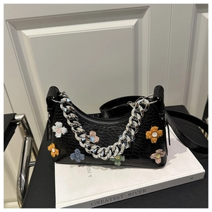 Macro detail of black crocodile pattern bag with colorful plush floral decorations