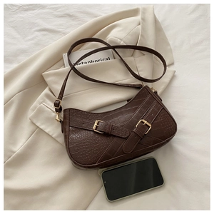 Close-up of brown crocodile texture leather bag with elegant gold buckle detail