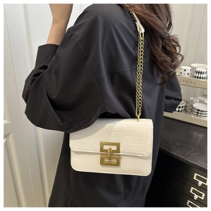 Close-up of white crocodile pattern shoulder bag with golden chain and clasp detail