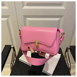 Detail of a pink leather shoulder bag with a gold metal capsule lock held by a model