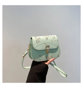 Detail of mint green crossbody bag with floral embroidery and golden metal clasp
