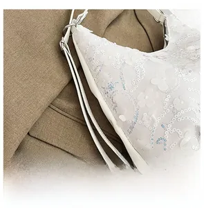 Détails de la broderie florale à paillettes blanches et ferrures argentées sur le sac