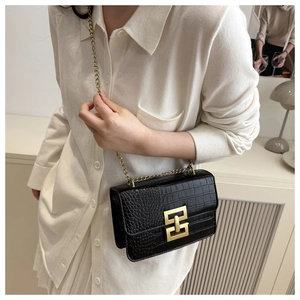 Detail of black faux crocodile leather crossbody bag with gold clasp and chain strap