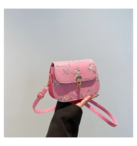 Close-up of pink lace floral embroidery and gold metal clasp on mini crossbody bag