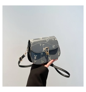 Detailed close-up of vintage floral embroidery and golden metal clasp on a small square bag