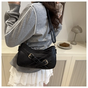 Detailed close-up of black crocodile pattern faux leather bag with golden metal buckles