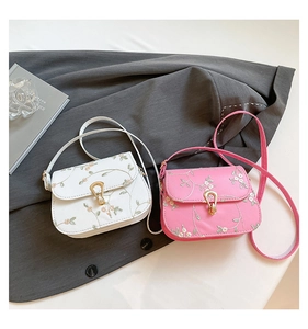 Detail of floral lace embroidery and golden drop-shaped twist lock on small square bags