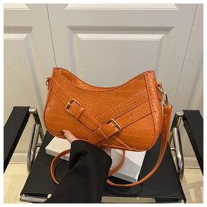 Detail of bright orange faux crocodile skin texture and gold buckle on a retro shoulder bag