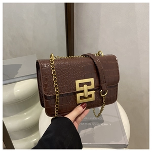 Detail of brown crocodile textured bag with gold square buckle and chain strap