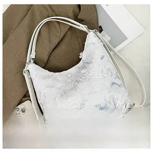 Détail de la dentelle florale 3D blanche et des paillettes sur la surface du sac à main