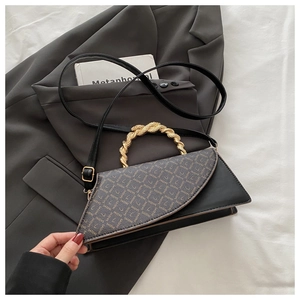 Macro shot of the twisted gold handle and leather texture on this chic crossbody bag