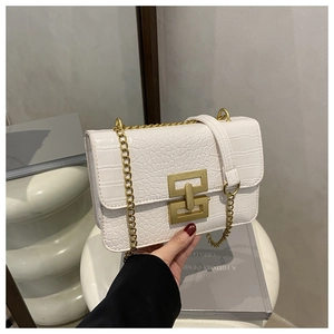 Detail of white crocodile pattern shoulder bag with a gold metal lock and chain strap