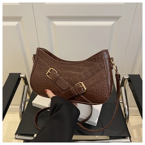 Detail of dark brown faux crocodile leather underarm bag with gold buckles and crescent shape