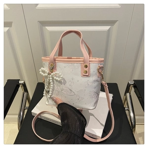 Detail of canvas bucket bag with butterfly print, pink trim and pearl bow charm