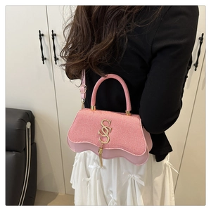 Detail of pink crossbody bag with wave-textured fabric and gold metal SS logo with tassel