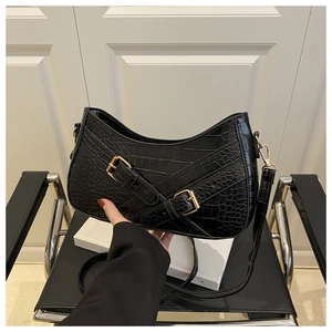 Close-up of black crocodile pattern faux leather with decorative gold buckles on the shoulder bag