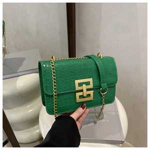 Detail of green crocodile-embossed leather crossbody bag with a matte gold buckle