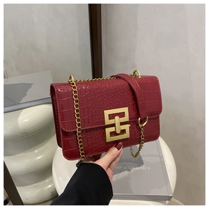 Close-up of red crocodile pattern handbag featuring a gold geometric metal buckle and chain