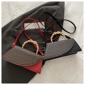 Detail of red and black leather handbags with gold textured handles on grey blazer