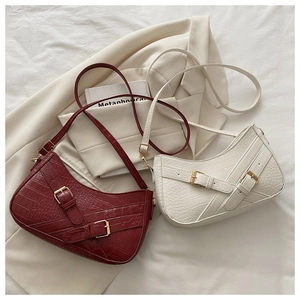 Detail of burgundy and cream faux crocodile leather hobo bags with metallic buckles
