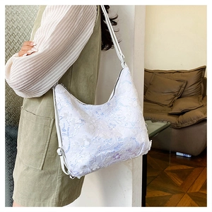Détail du sac hobo blanc avec broderie florale et paillettes scintillantes sur la bandoulière