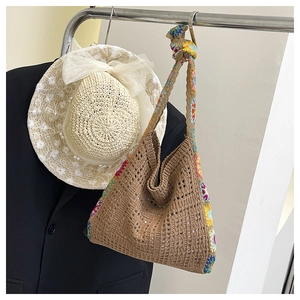 Detail of bohemian brown crochet tote bag with colorful floral patterns and white straw hat
