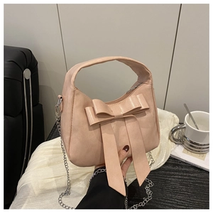 Détail du sac rose avec un grand nœud décoratif et une bandoulière en chaîne argentée