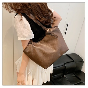 Detailed macro view showing the natural leather texture and metal buckle on the brown tote bag