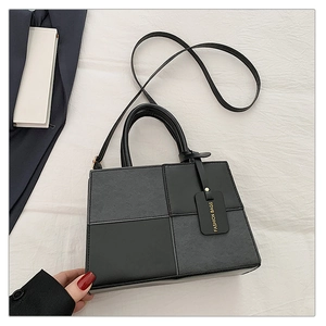 Detail of minimalist black patchwork handbag featuring a mix of matte and smooth faux leather