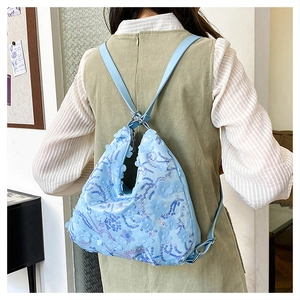 Détail du sac bleu clair à paillettes avec appliques florales et bandoulière réglable