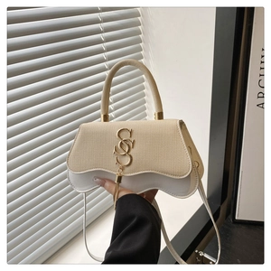 Detail of beige woven and white leather handbag with gold logo and tassel accent