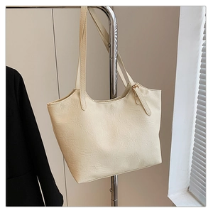 Detail of cream tote bag with vintage wrinkled leather texture and slim shoulder straps