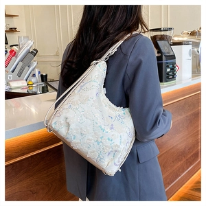 Détail du sac à paillettes avec fleurs 3D et textures ondulées sur sac à bandoulière crème