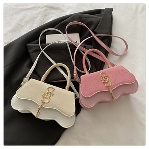 Detail of trendy crossbody bags with wavy bottom and gold letter logo with tassels