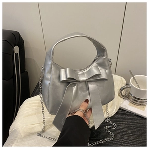 Détail du sac bandoulière argenté brillant avec grand nœud et fine bandoulière chaîne