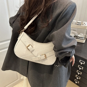 Stylish white crocodile pattern shoulder bag with golden buckles shown on a model