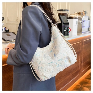 Détail du sac à bandoulière blanc à paillettes et fleurs 3D porté dans un café
