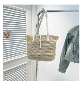 Vue détaillée du sac cabas en paille tissée avec anses en simili cuir blanc et boucle