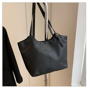Detail of black vintage tote bag showing wrinkled leather texture and gold buckle