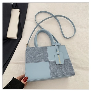 Light blue crossbody bag with mixed textures, round handle and decorative fashion tag