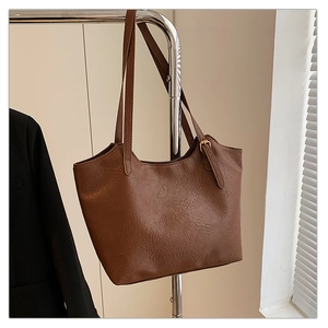 Detail of vintage brown tote bag with textured faux leather on a studio hanger