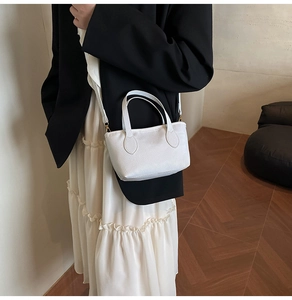 Mini white pebbled leather bucket bag styled with a black blazer and white dress