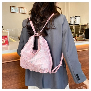Détail d'un sac à dos rose à paillettes avec des fleurs en organza 3D élégantes