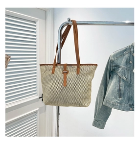 Détail du sac cabas en paille tissée avec lanières en cuir marron et boucle en métal