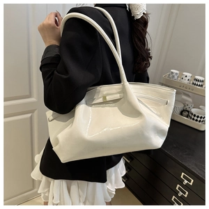 Borsa tote in pelle verniciata bianca lucida indossata a spalla con un design moderno