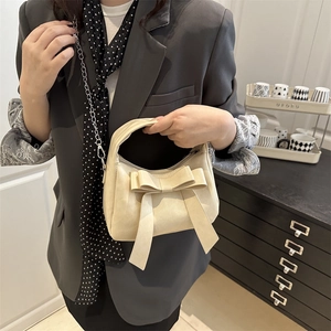 Sac à main élégant crème avec nœud et bandoulière chaîne dans un style de vie chic