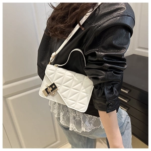 Détail de sac à bandoulière matelassé blanc avec fermoir doré sur une veste en cuir noir chic