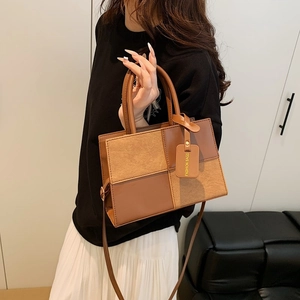 Brown leather patchwork crossbody bag with round handles shown in a modern interior