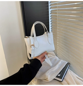 Detail of white litchi pattern leather handbag with elegant gold hardware and strap
