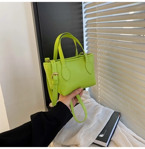 Detail of lime green mini bucket bag with lychee texture and golden hardware accents